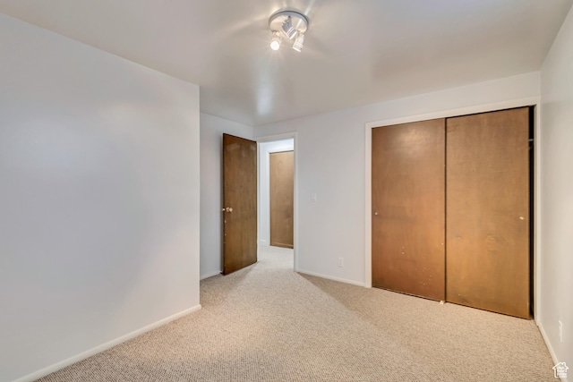 unfurnished bedroom with carpet, a closet, and baseboards