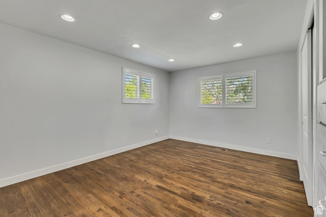 spare room featuring baseboards, dark wood-type flooring, and recessed lighting