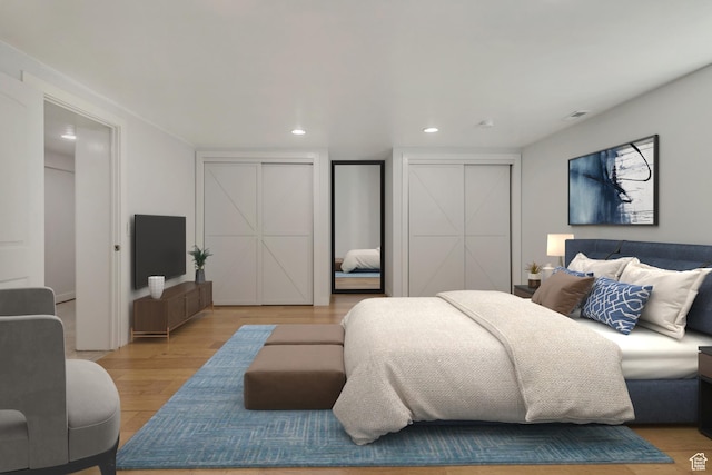 bedroom featuring light wood finished floors, visible vents, multiple closets, and recessed lighting