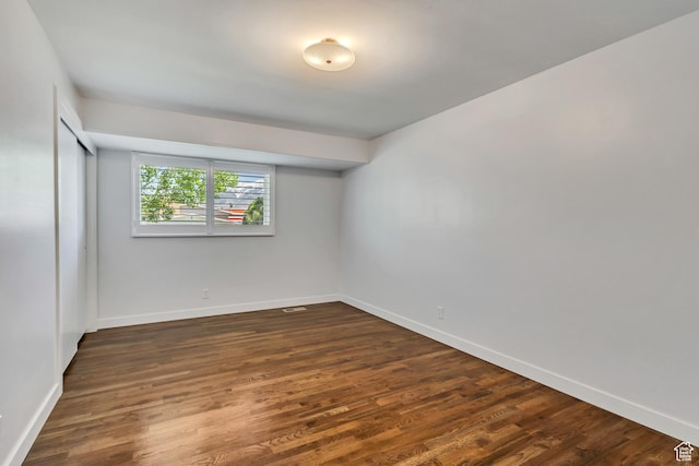 empty room with baseboards and dark wood-style flooring
