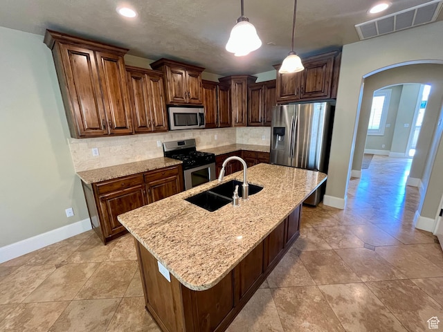 kitchen featuring a sink, stainless steel appliances, visible vents, arched walkways, and tasteful backsplash