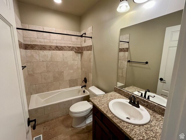 bathroom with toilet, tiled shower / bath combo, vanity, and visible vents