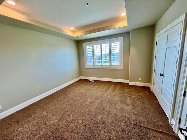 unfurnished bedroom with dark colored carpet, baseboards, a raised ceiling, and recessed lighting