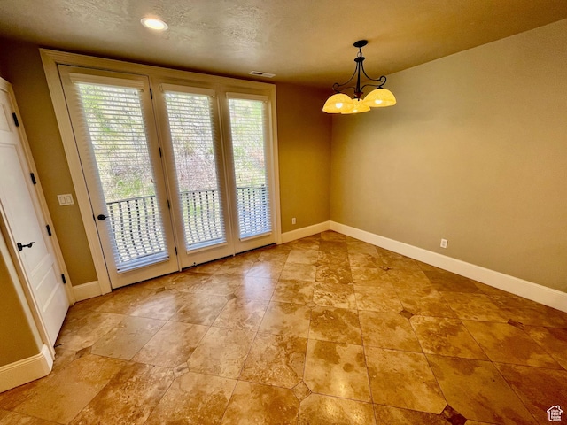 unfurnished dining area with baseboards, a notable chandelier, visible vents, and a textured ceiling