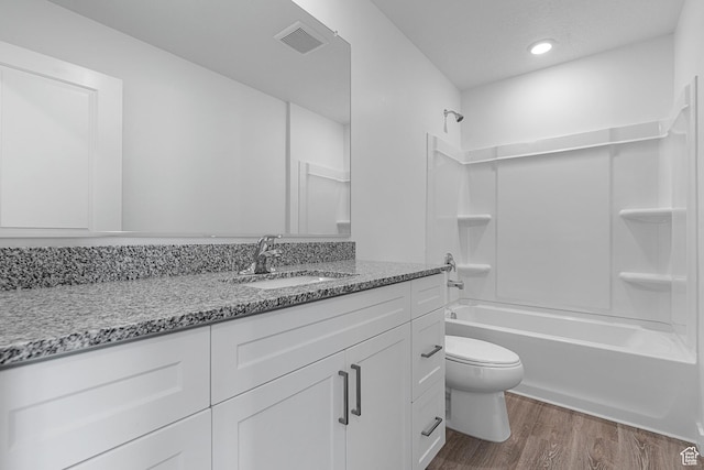 bathroom featuring toilet, wood finished floors, shower / tub combination, visible vents, and vanity