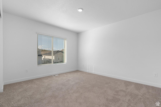 carpeted empty room featuring baseboards and visible vents
