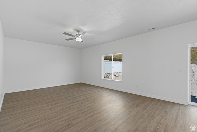 spare room featuring ceiling fan, baseboards, visible vents, and wood finished floors