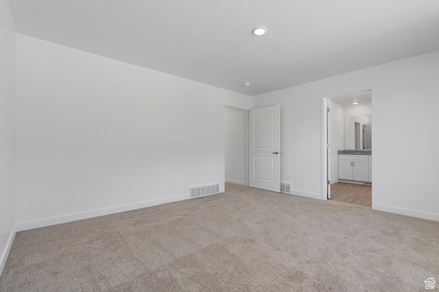 unfurnished bedroom featuring light colored carpet, baseboards, and visible vents