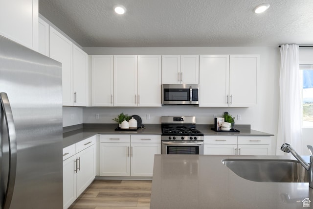 2522 N Wildwood Ln E Unit 240, Heber City, UT 84032 - kitchen featuring stainless steel appliances, dark countertops, a textured ceiling, white cabinetry, and light wood finished floors