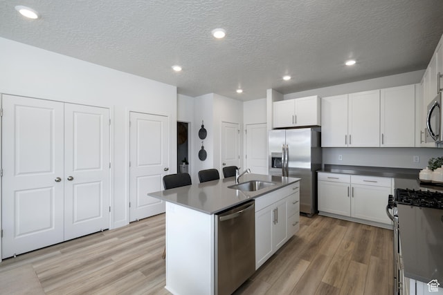 2522 N Wildwood Ln E Unit 240, Heber City, UT 84032 - kitchen featuring stainless steel appliances, light wood-style flooring, a kitchen island with sink, white cabinets, and a textured ceiling