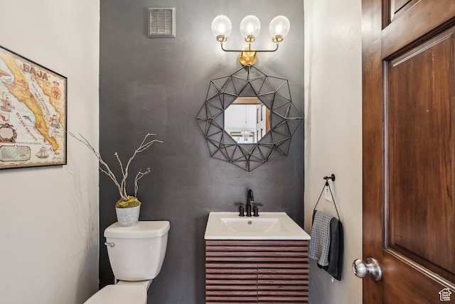 bathroom featuring toilet, vanity, and visible vents