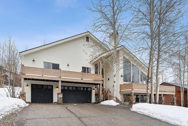 exterior space with aphalt driveway, stairs, stucco siding, and stone siding
