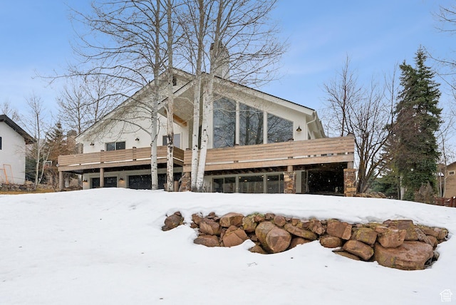 snow covered rear of property with stone siding
