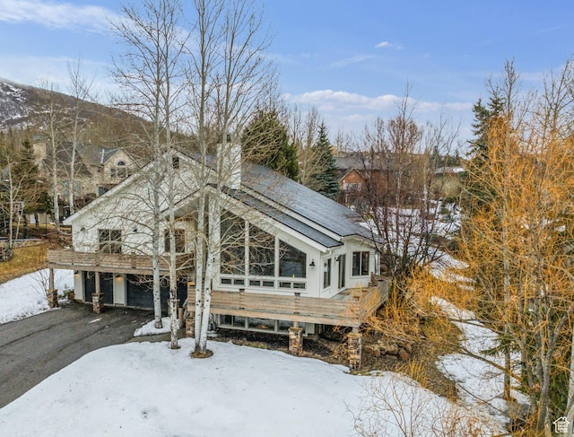 view of front of home featuring a wooden deck, a garage, a chimney, and driveway