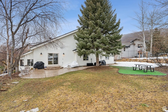 rear view of house featuring a yard, entry steps, a patio area, and stucco siding