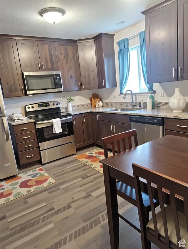 621 Shay Ln, Tooele, UT 84074 - kitchen featuring stainless steel appliances, a sink, dark brown cabinetry, and light stone countertops