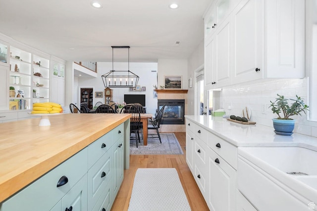 1056 W 100 N, St George, UT 84770 - kitchen with tasteful backsplash, decorative light fixtures, light wood-style flooring, white cabinetry, and glass insert cabinets