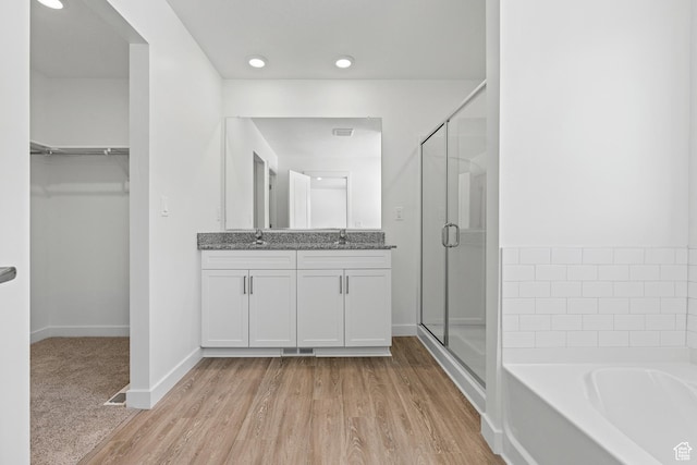 bathroom featuring a sink, wood finished floors, a spacious closet, a shower stall, and a bath