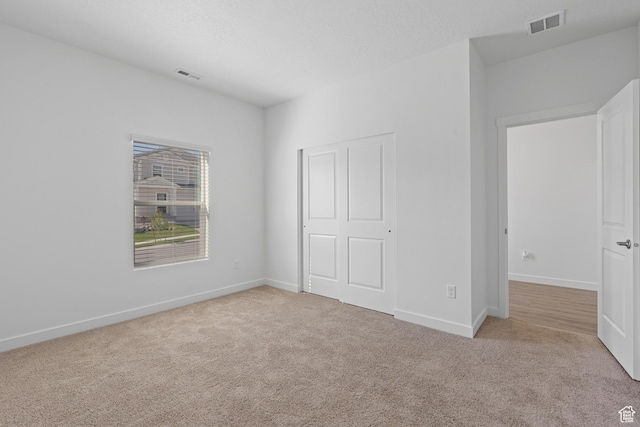 unfurnished bedroom with carpet flooring, baseboards, and visible vents