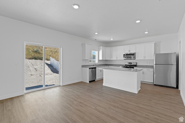 kitchen with white cabinetry, stainless steel appliances, light wood-style flooring, and a kitchen island