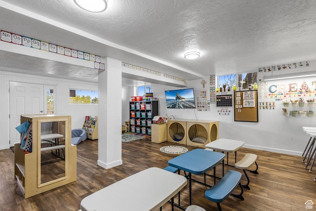 playroom with a textured ceiling, baseboards, and wood finished floors