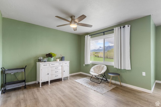 living area featuring baseboards, wood finished floors, and a ceiling fan