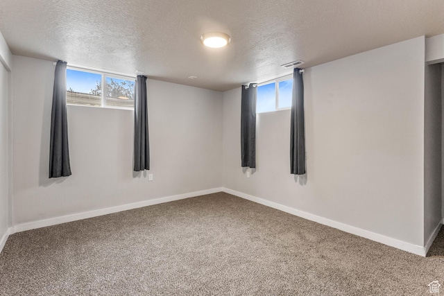 carpeted empty room with a textured ceiling, baseboards, and a healthy amount of sunlight