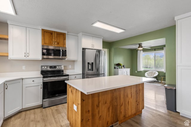 kitchen featuring light wood-style flooring, light countertops, a center island, and appliances with stainless steel finishes
