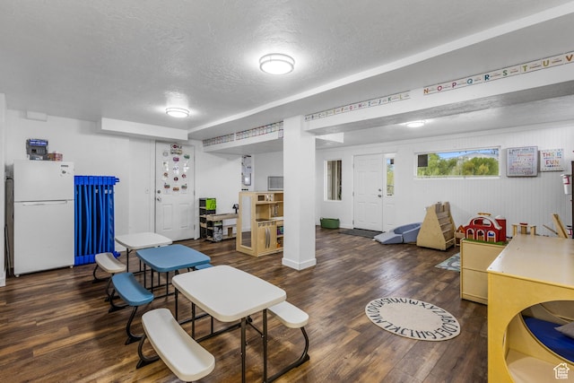 interior space with a textured ceiling, wood finished floors, and baseboards