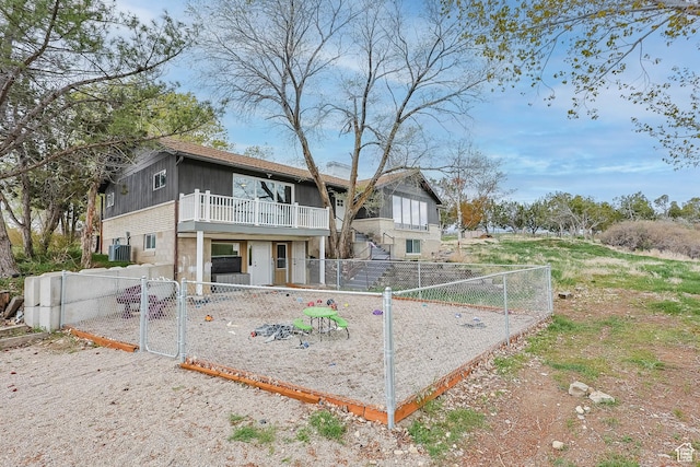back of property featuring central air condition unit, a gate, fence private yard, and a balcony