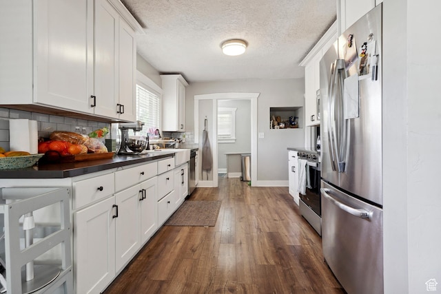 1923 S 600 E, Salt Lake City, UT 84105 - kitchen featuring white cabinetry, decorative backsplash, dark countertops, appliances with stainless steel finishes, and dark wood-style floors
