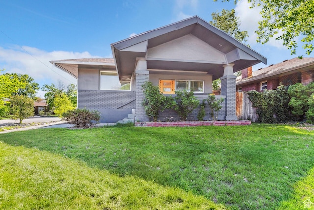 view of front of home featuring a front lawn, brick siding, and stucco siding