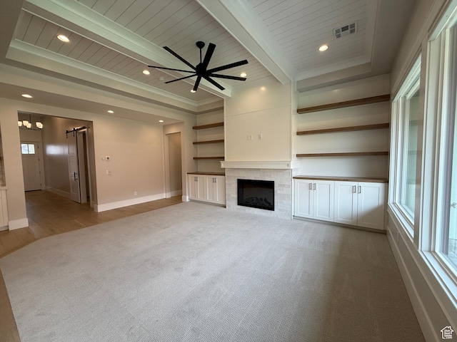 unfurnished living room with a barn door, a wealth of natural light, carpet floors, and visible vents