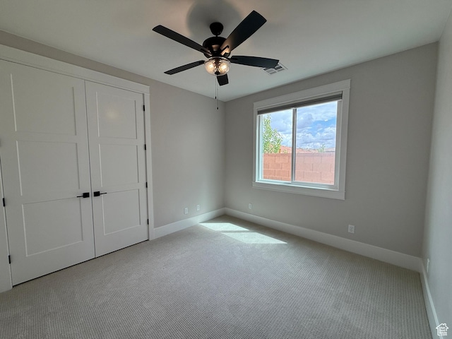 unfurnished bedroom with a closet, carpet, visible vents, ceiling fan, and baseboards