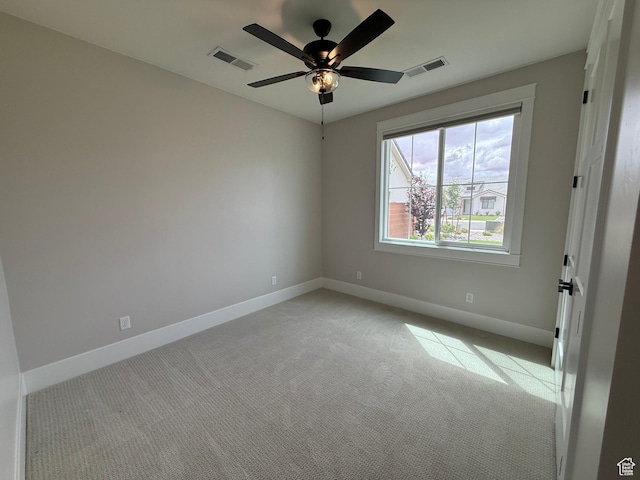 empty room with baseboards, light carpet, visible vents, and a ceiling fan
