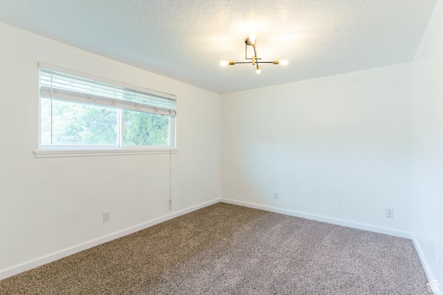 carpeted empty room with baseboards, a chandelier, and a textured ceiling