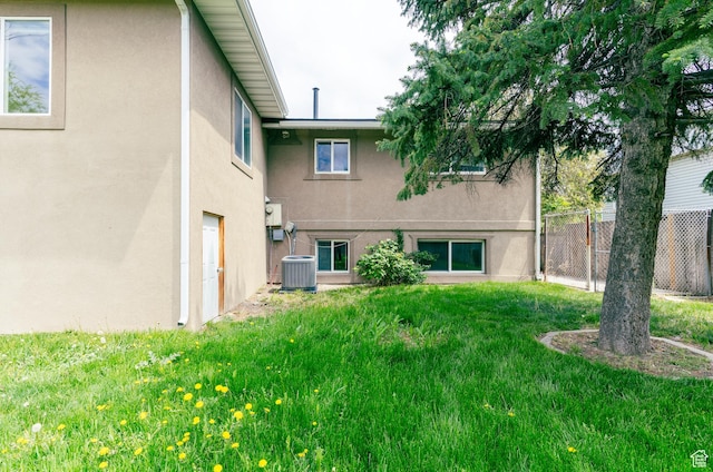 back of house with a yard, fence, stucco siding, and cooling unit