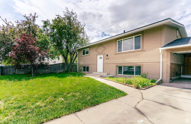 back of property with a yard, fence, stucco siding, and concrete driveway