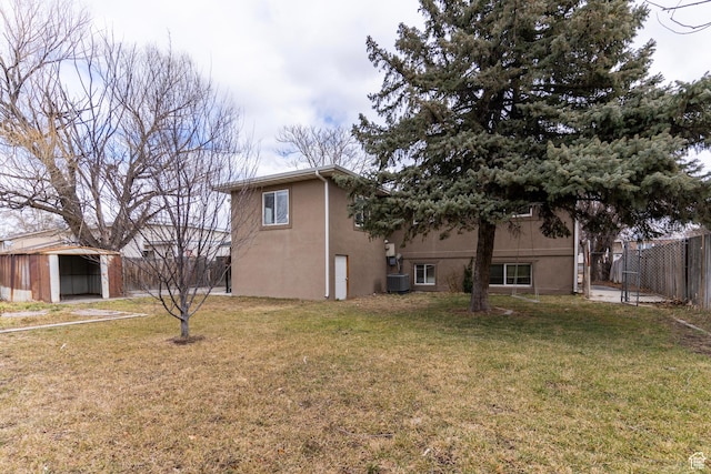 exterior space featuring central AC, stucco siding, fence, and a lawn