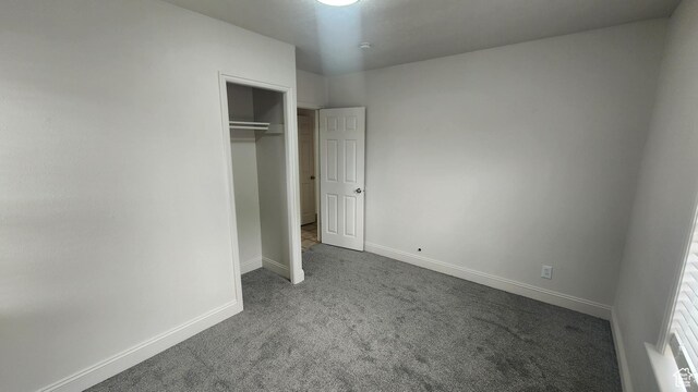 unfurnished bedroom with baseboards, carpet flooring, and a closet