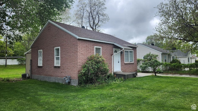 view of side of property with a lawn, central air condition unit, and brick siding