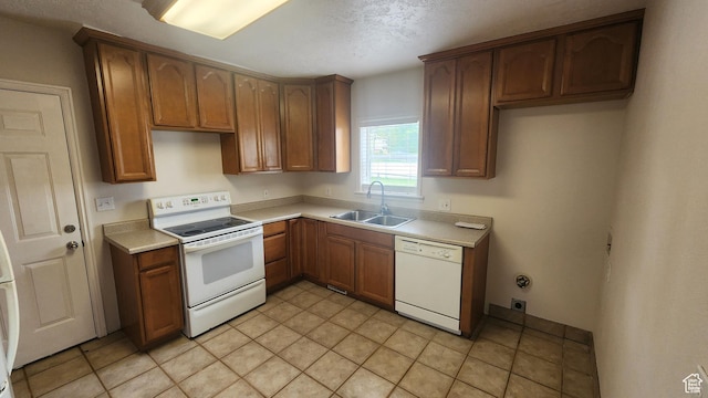 kitchen featuring light countertops, brown cabinets, a sink, and white appliances