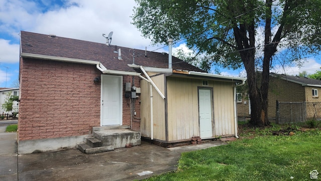 back of house with a yard, fence, and a shingled roof