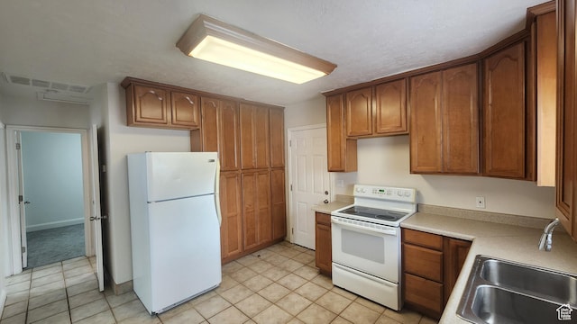 kitchen featuring a sink, white appliances, light tile patterned floors, and visible vents