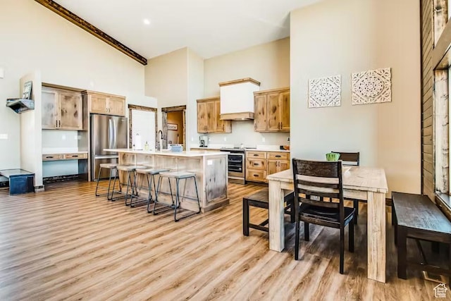 2869 S Chukar Dr Unit 63, Garden City, UT 84028 - kitchen featuring light wood-style flooring, appliances with stainless steel finishes, a towering ceiling, and a kitchen bar