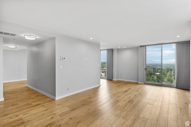 777 E S Temple S Unit 11B, Salt Lake City, UT 84102 - spare room featuring expansive windows, baseboards, light wood-type flooring, and recessed lighting