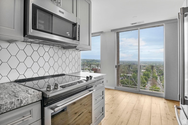 777 E S Temple S Unit 11B, Salt Lake City, UT 84102 - kitchen with tasteful backsplash, light wood-type flooring, gray cabinets, and appliances with stainless steel finishes