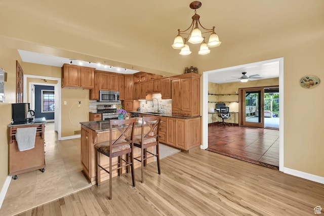 kitchen with stainless steel appliances, baseboards, a center island, and light wood-style floors