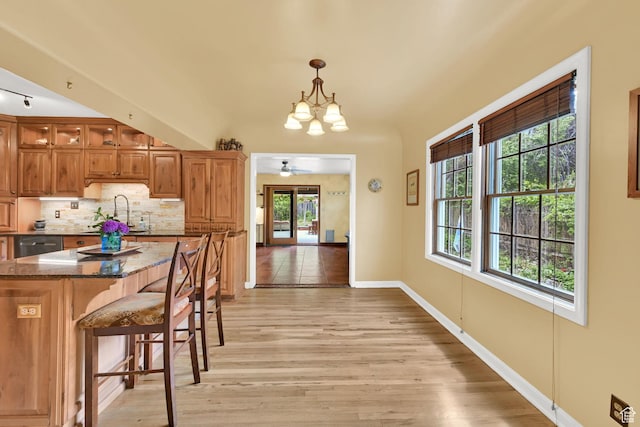kitchen featuring a chandelier, a sink, light wood-style flooring, and decorative backsplash
