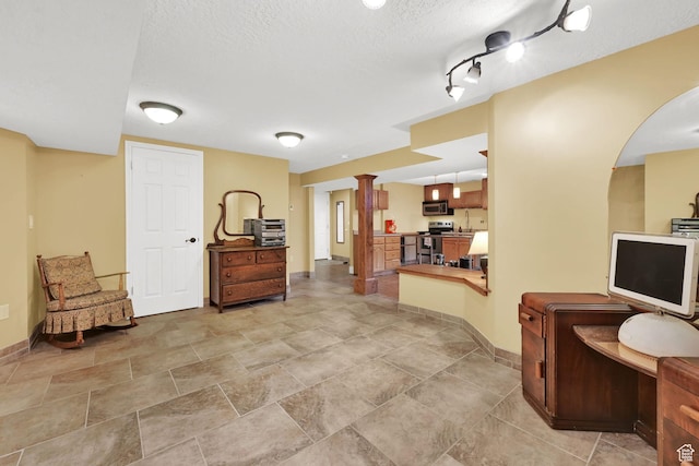 sitting room with baseboards, a textured ceiling, and arched walkways